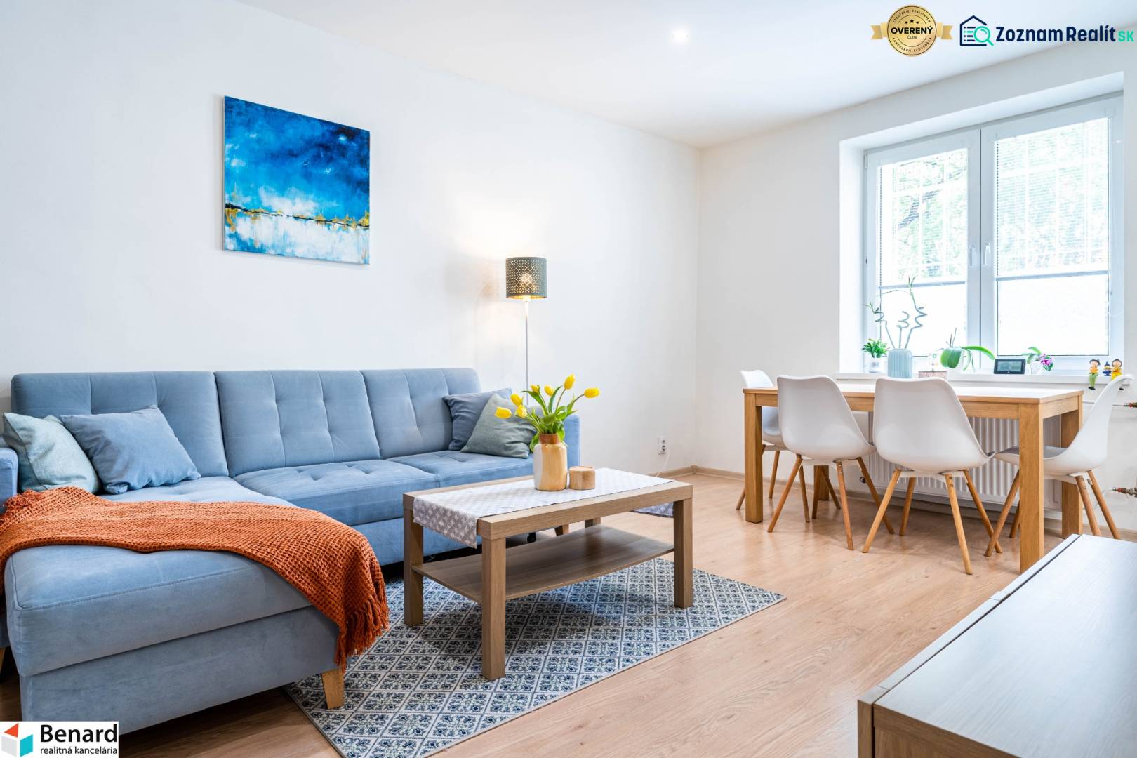 Living room in a three-room apartment with a sofa and a dining table, floor with wood decor.