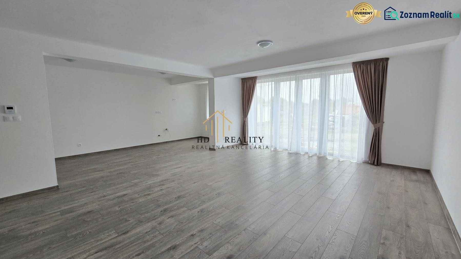 Living room in a family house with a floor and light walls and large windows.