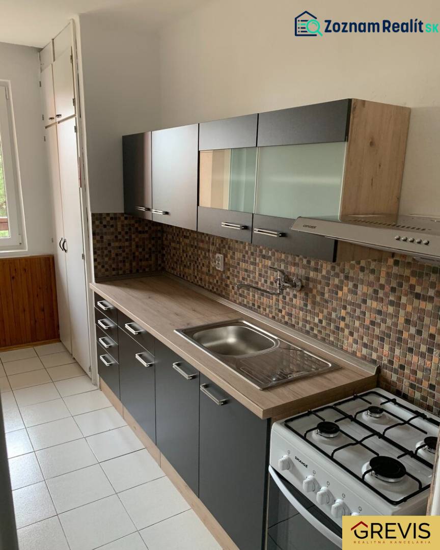 A kitchen in a 2-room apartment with mosaic tiles and a floor with a wooden decor.