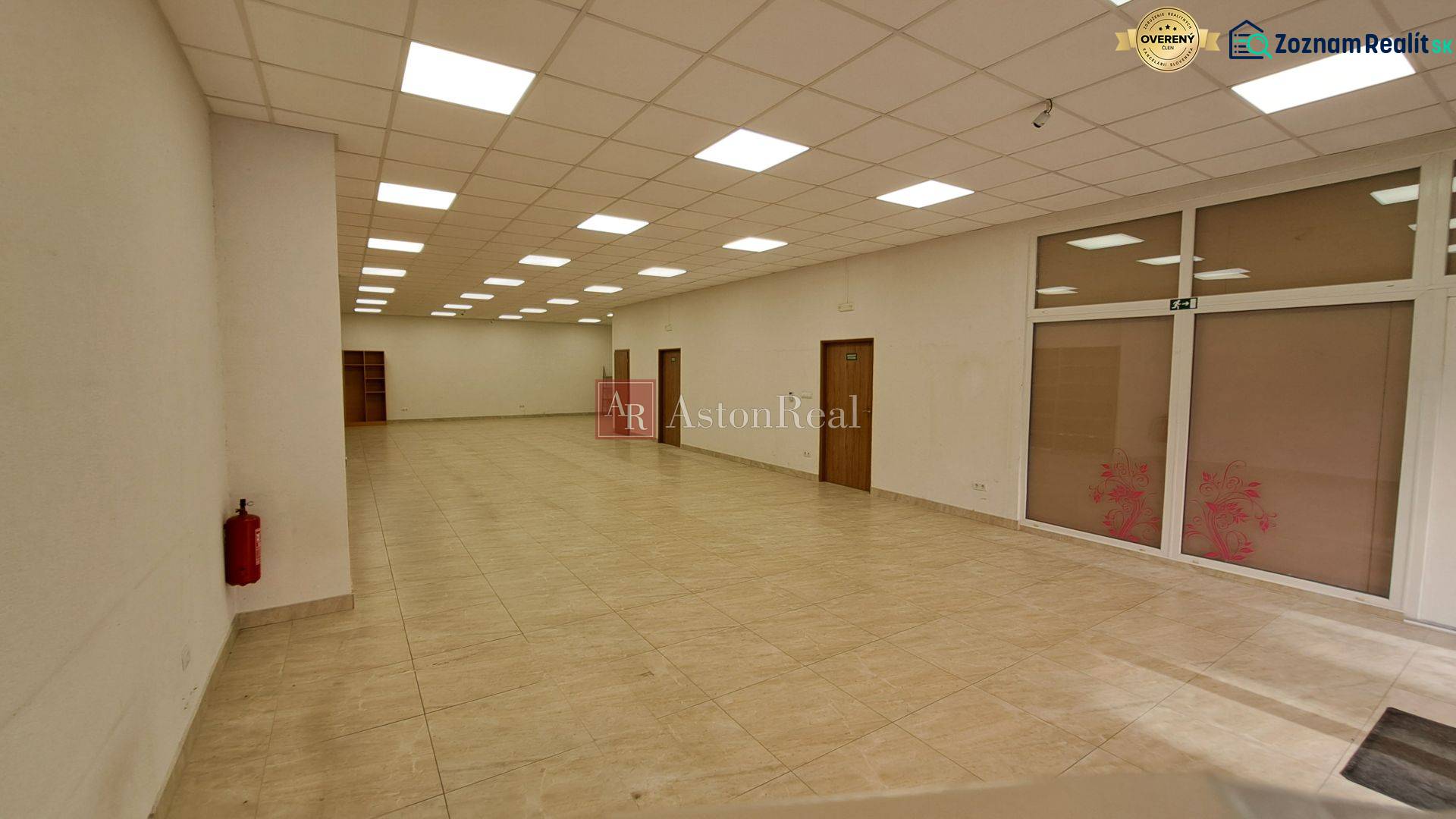 Space with tiles, ceiling lights, and doors in commercial premises.
