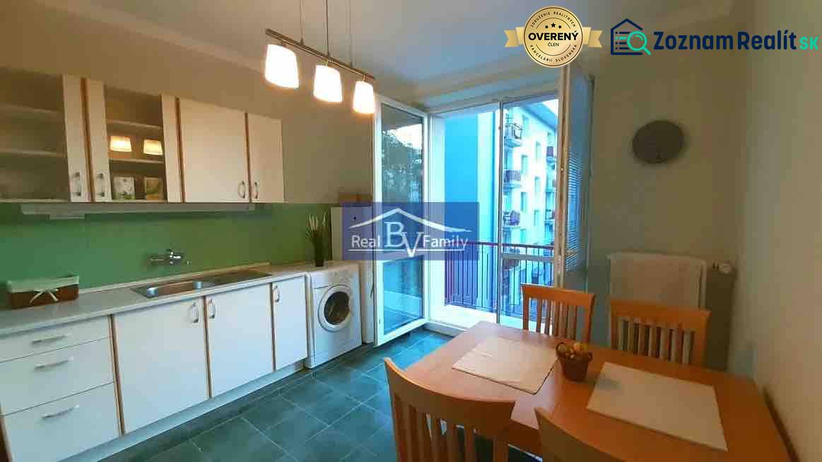 A kitchen in a 2-room apartment with white cabinets, a dining table, and a balcony.
