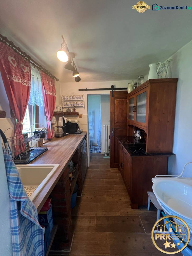 A kitchen in a wooden cabin with rustic furniture, a sink, and decorative curtains.