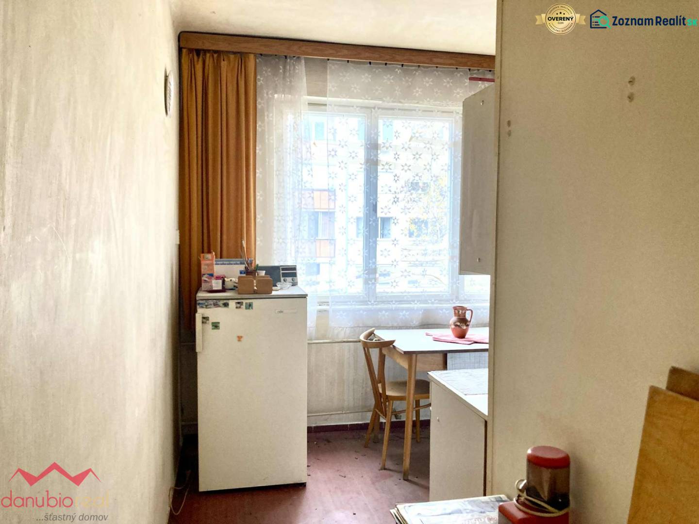 A kitchen in a 3-room apartment with a wooden decor floor, simple furnishings, and a window.