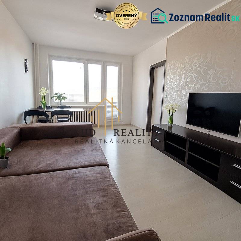 Living room in a 3-room apartment with a large sofa, TV, and flooring with a wooden decor.