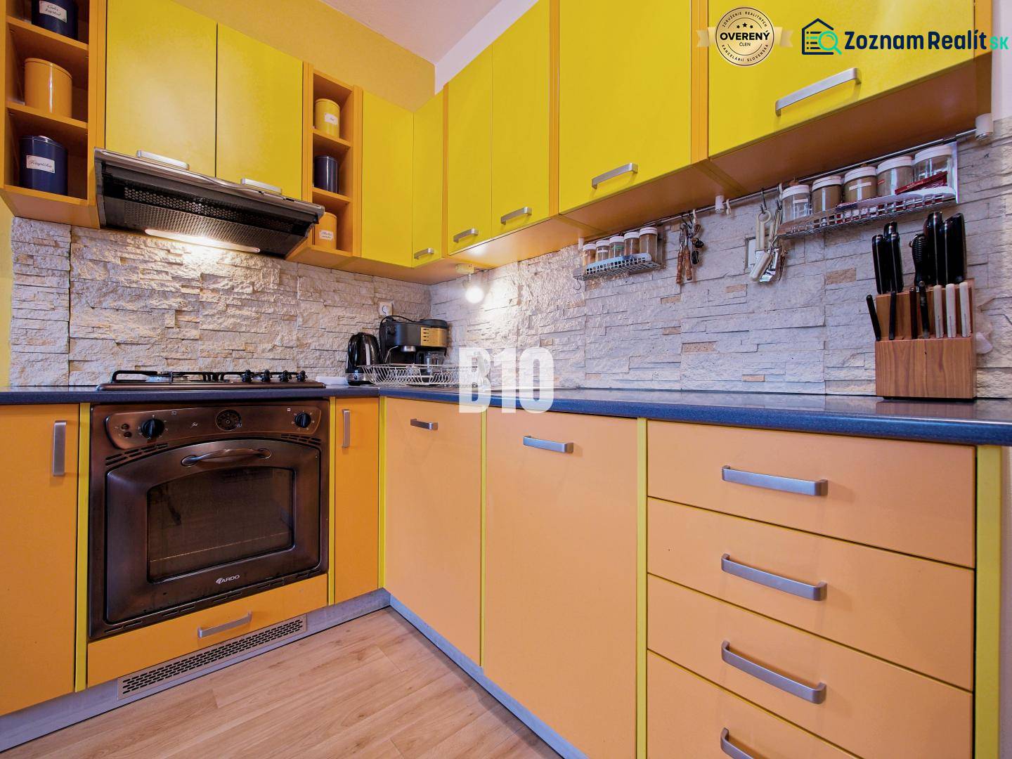 A kitchen in a 2-room apartment with a colorful kitchen unit and a wooden decor floor.