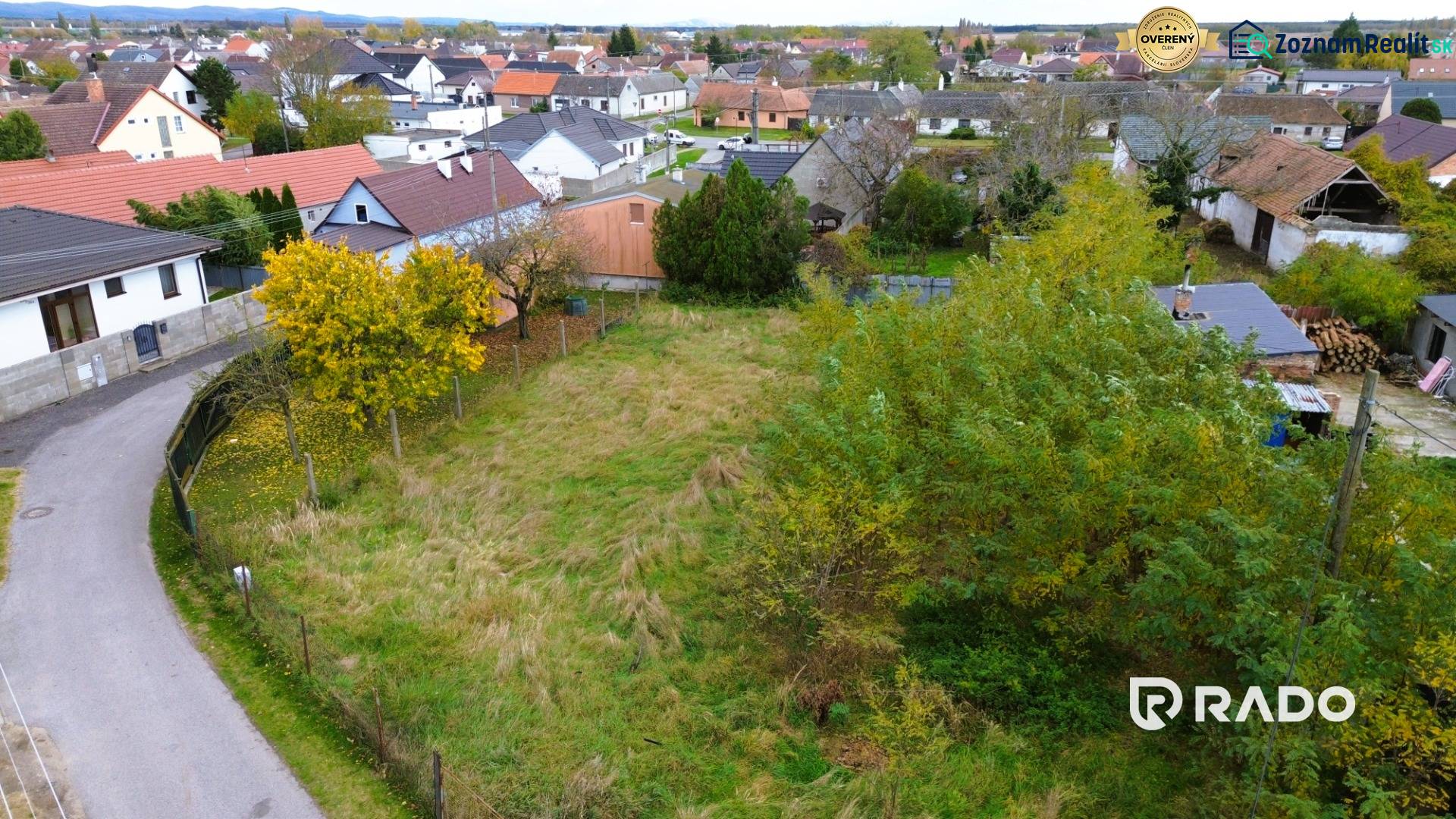 A plot of land in Gajary, designated for residential use, surrounded by neighboring houses.