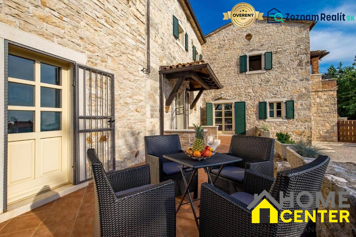 Stone facade of a villa in Bale with outdoor seating and fruit on the table.