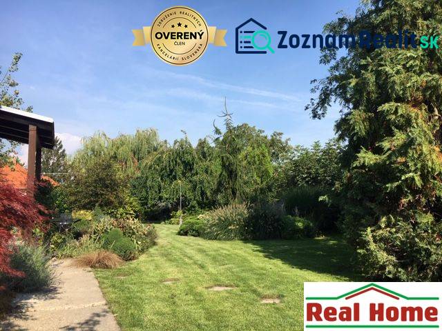 The garden at the family house in Čierna Voda with rich planting and well-maintained lawn.