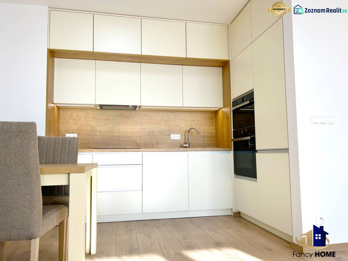 A kitchen in a 2-room apartment with white cabinets and a floor with a wood design.