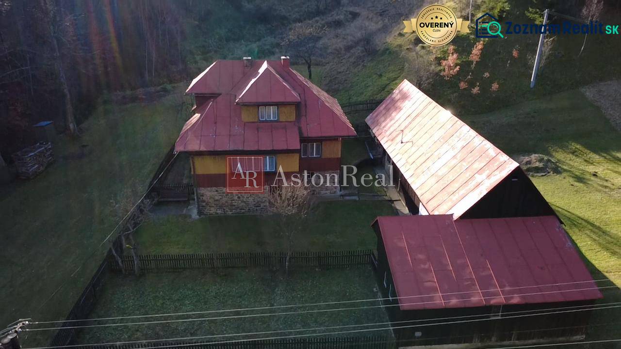 A family house in Zázrivá surrounded by nature, with a red roof and a wooden barn.