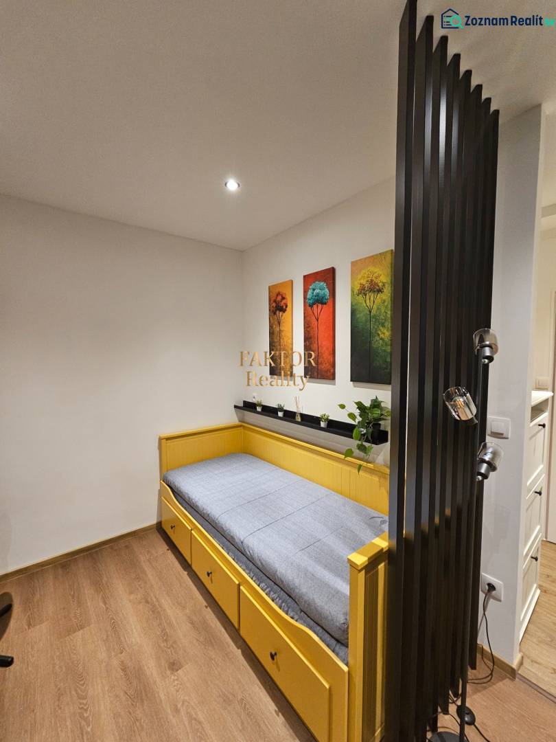 A studio apartment with a single bed, paintings of trees, and a floor with a wood decor.