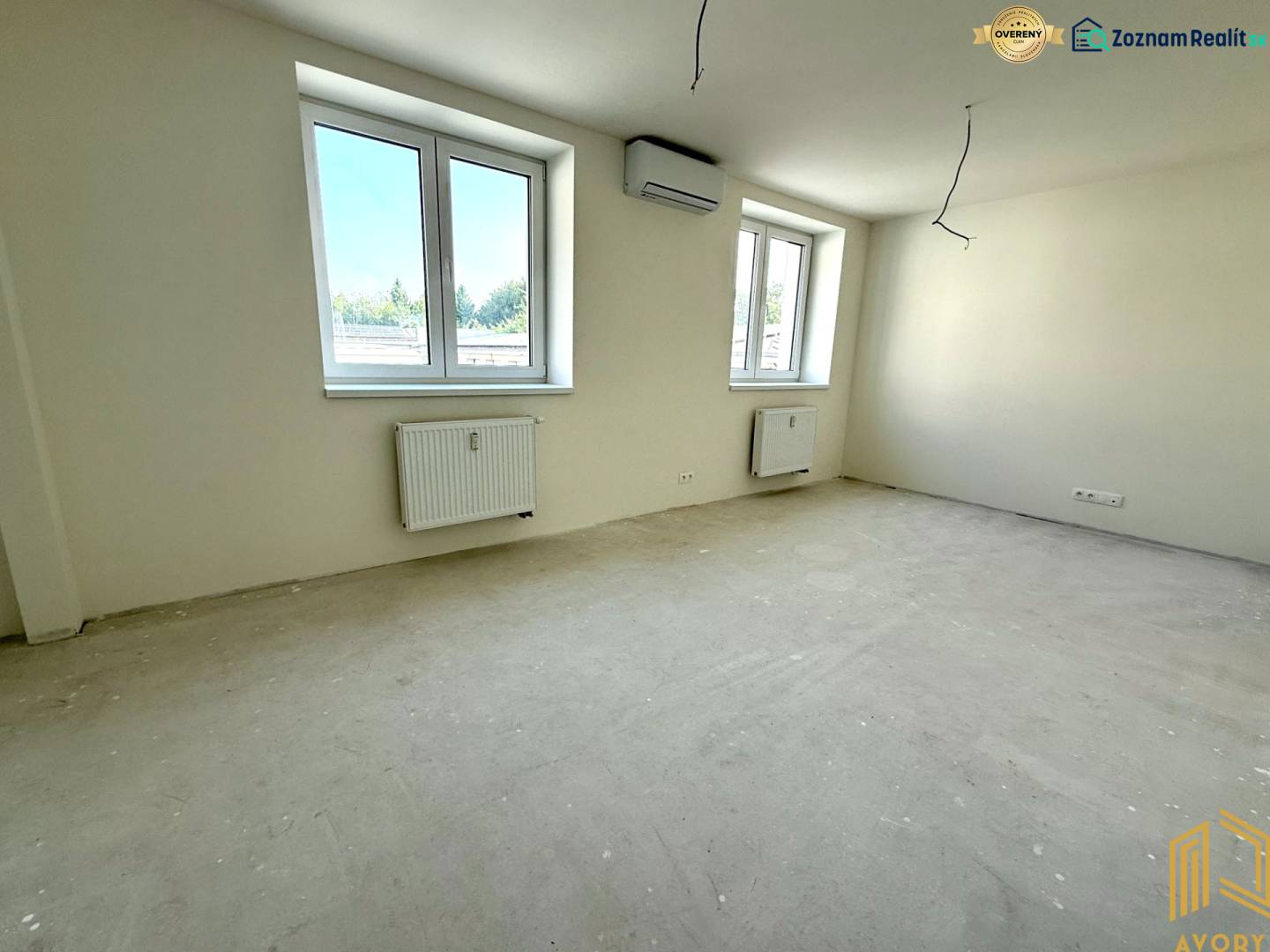A spacious room in a 2-room apartment with large windows and neutral walls.