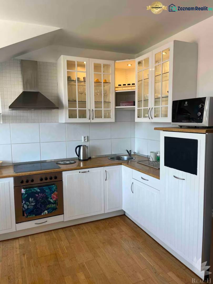 A kitchen in a 3-room apartment with wooden flooring, white cabinets, and storage space.