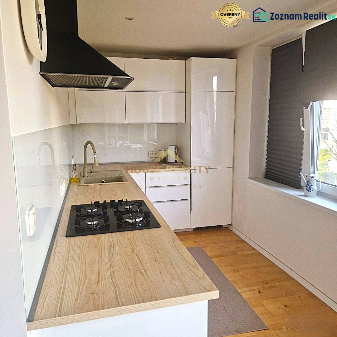 A kitchen in a 2-room apartment with white cabinets and a wooden-patterned floor.