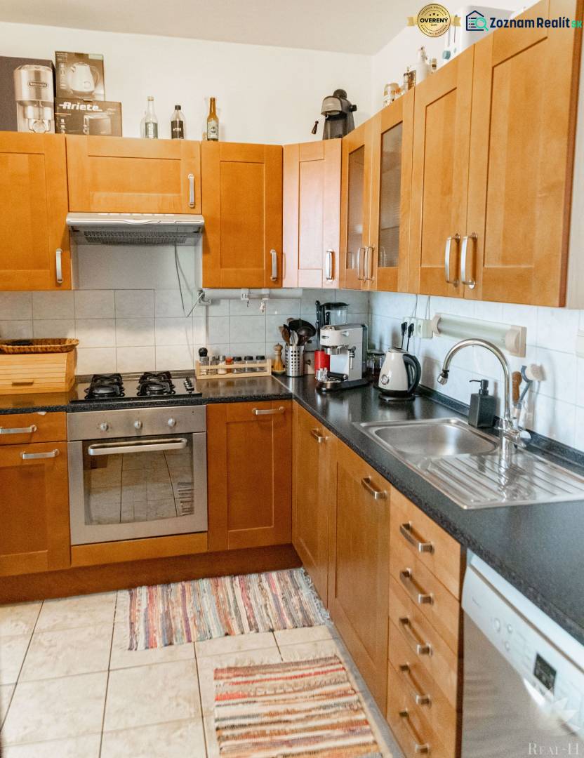 A kitchen in a 2-room apartment with brown cabinets, a stove, and a dishwasher.