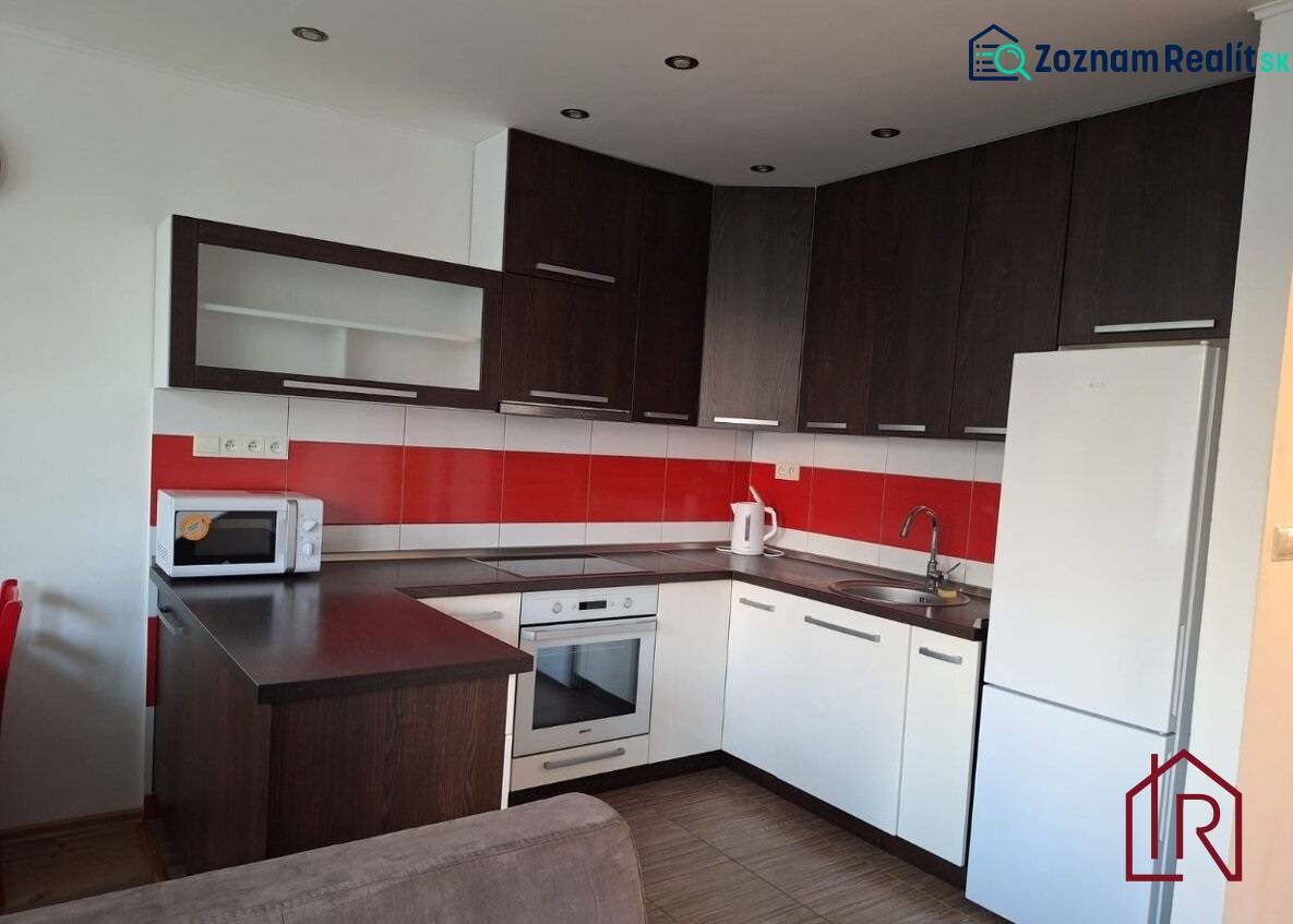 A kitchen in a 3-room apartment with white cabinets and red tiles, and a wooden decor floor.