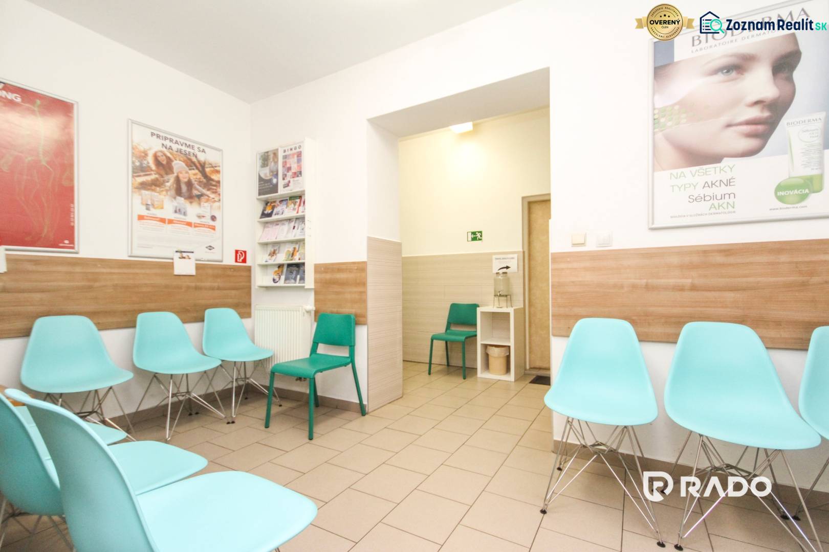 A waiting room with turquoise chairs, walls with wooden decor, medical posters on the walls.