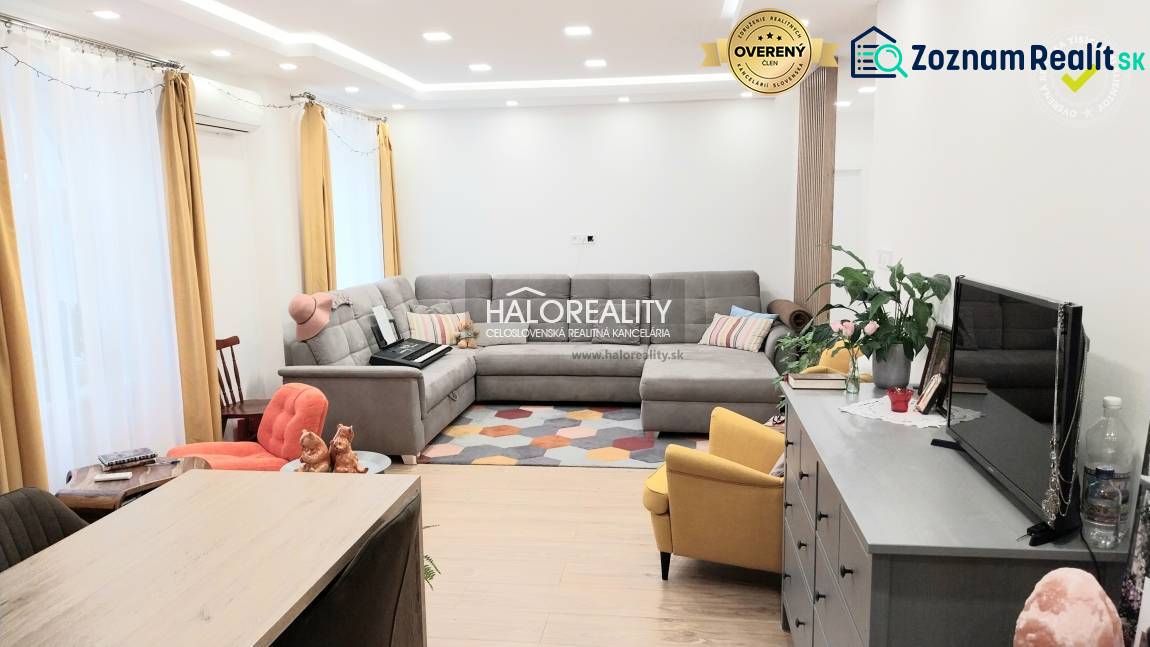 A living room in a three-room apartment with a wooden decor floor, a gray sofa, and a yellow armchair.