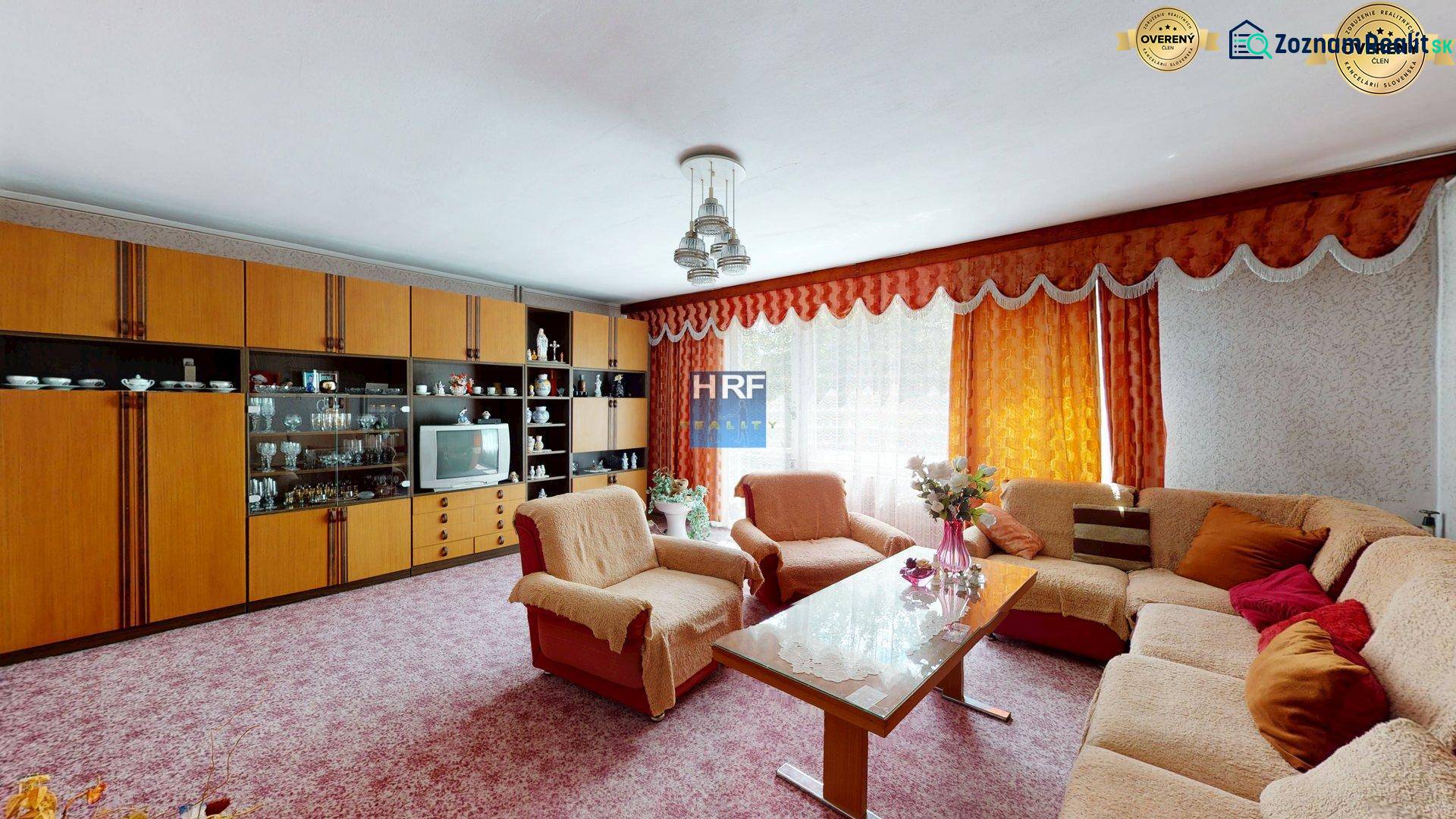Living room in a family house with a sofa set, a living room wall unit, and flowers.