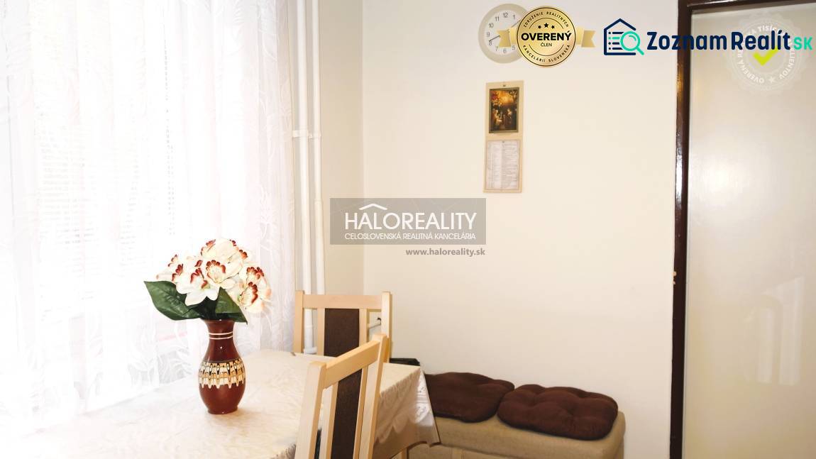 Dining area in a 3-room apartment with a flower on the table and a white curtain.