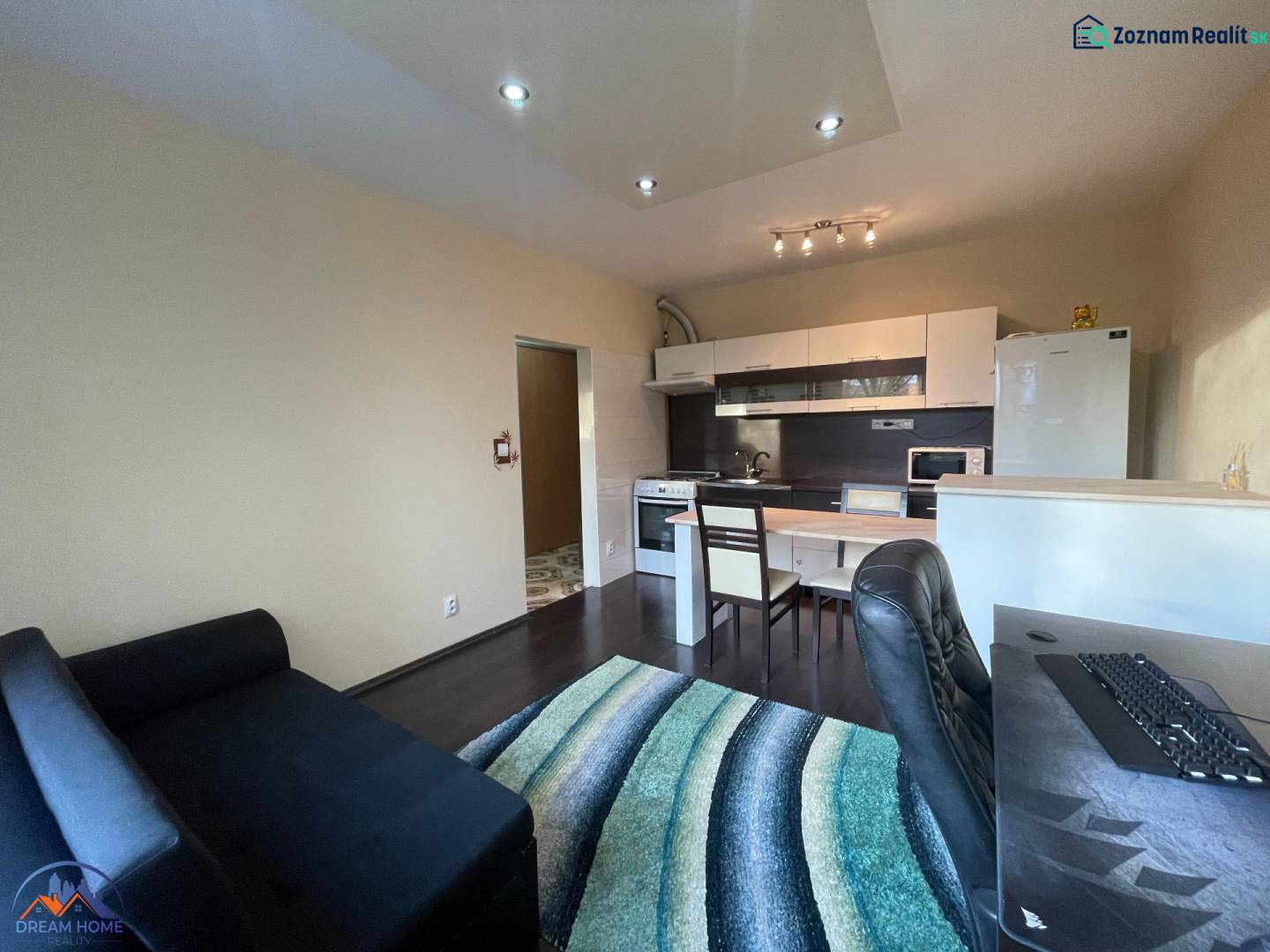 Interior of a 1-room apartment with a kitchenette and a wooden decor floor.
