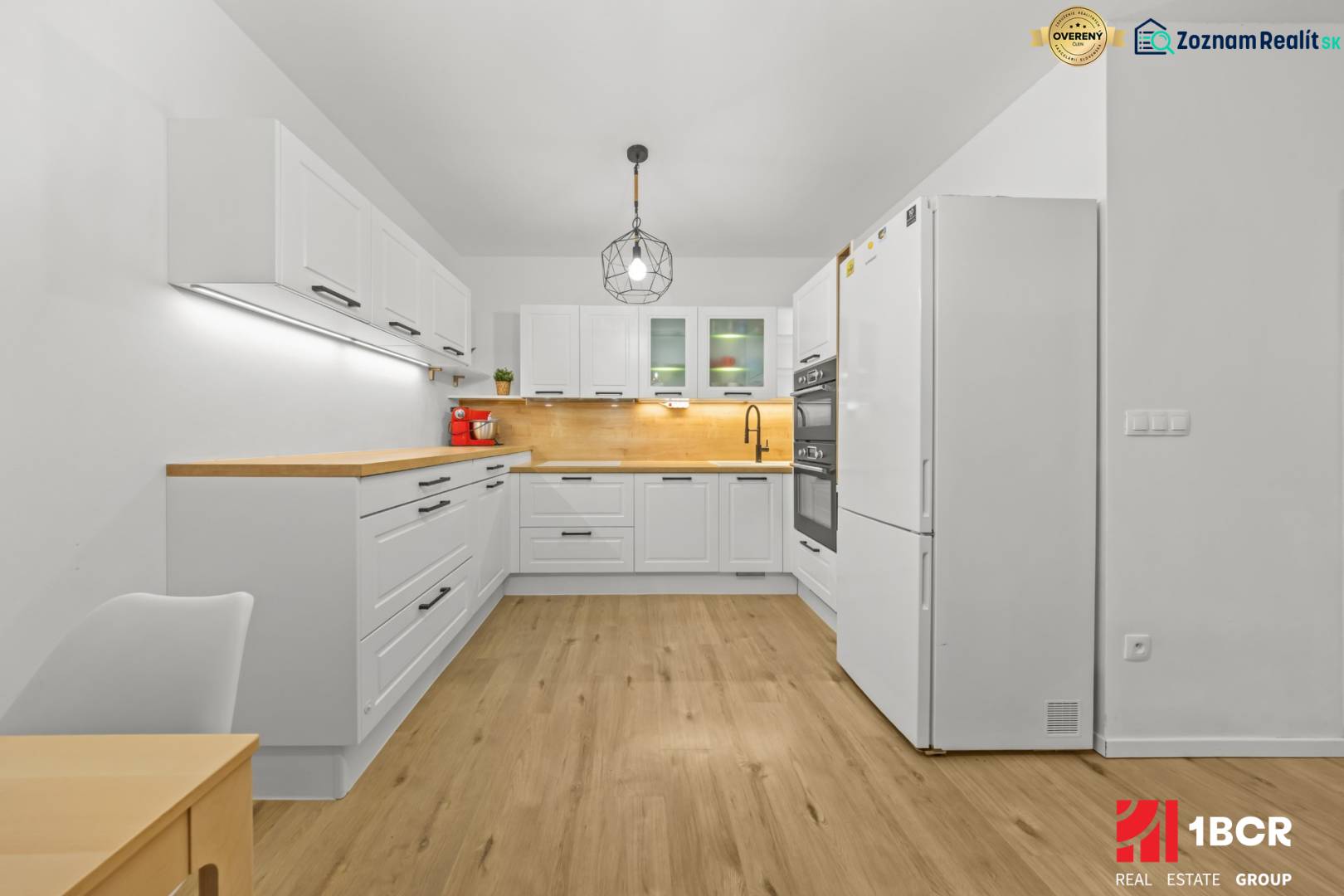 A kitchen in a 2-room apartment with white cabinets and a wood-patterned floor.