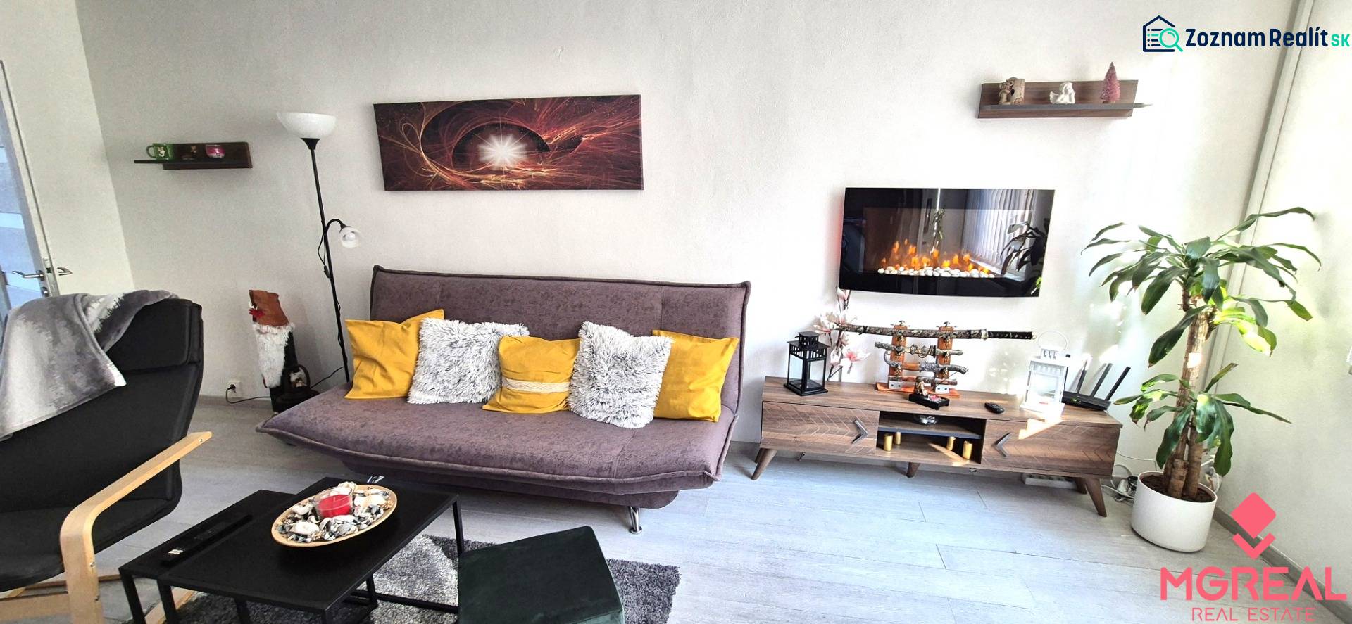 Living room in a two-room apartment with a sofa, shelf, and electric fireplace.