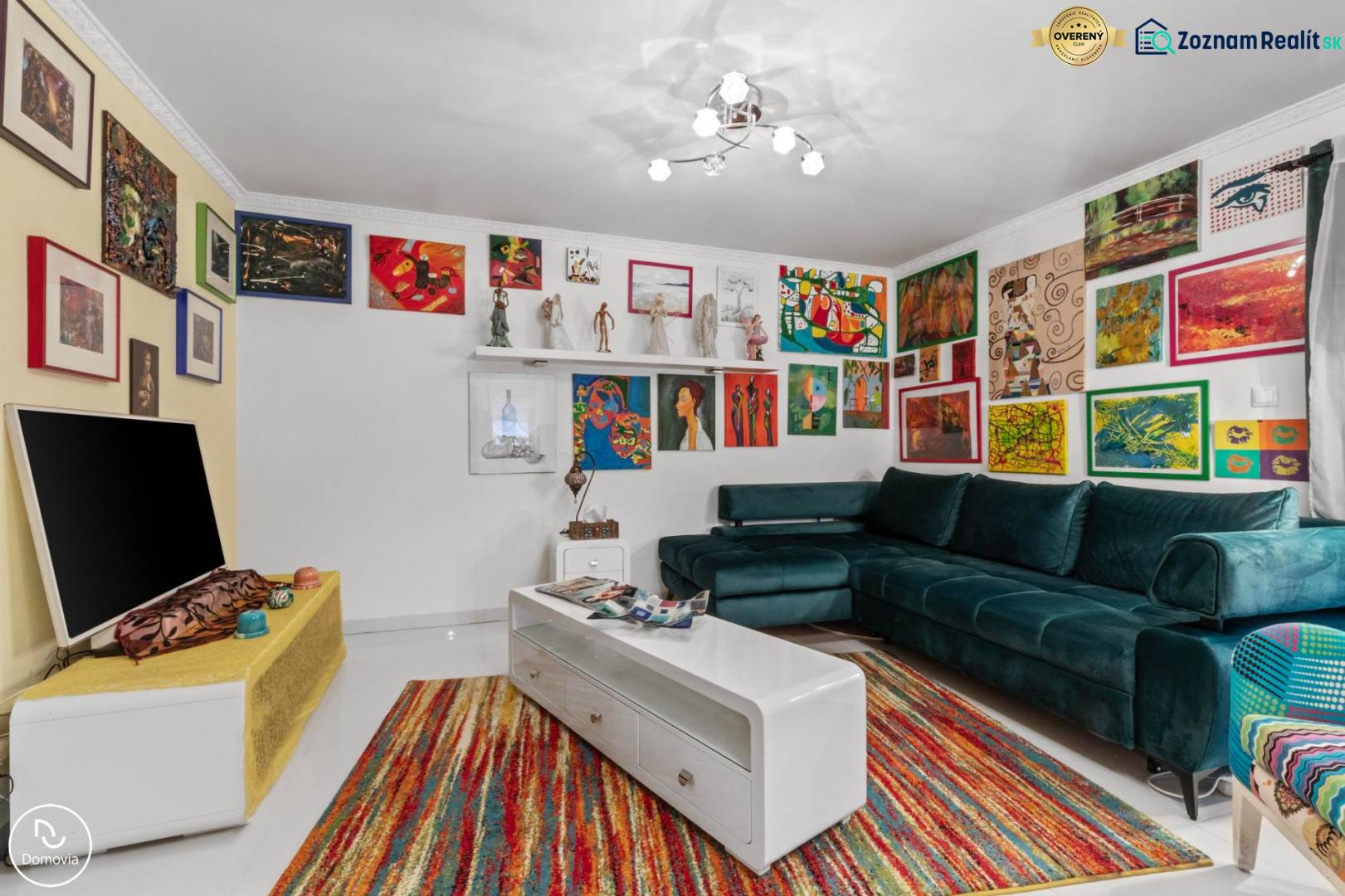 A colorfully decorated living room of a family house with a green sofa and artworks on the walls.