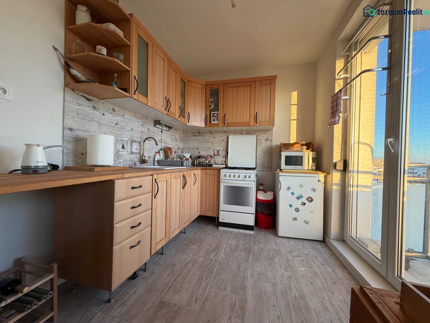 A kitchen in a 2-room apartment with wooden decor and appliances, including a small stove.