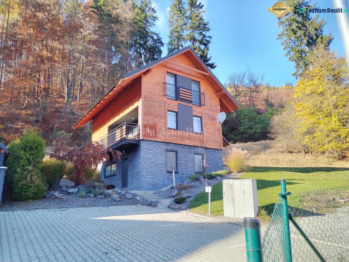 A cottage in Stráne in Martin surrounded by an autumn forest and a manicured lawn.