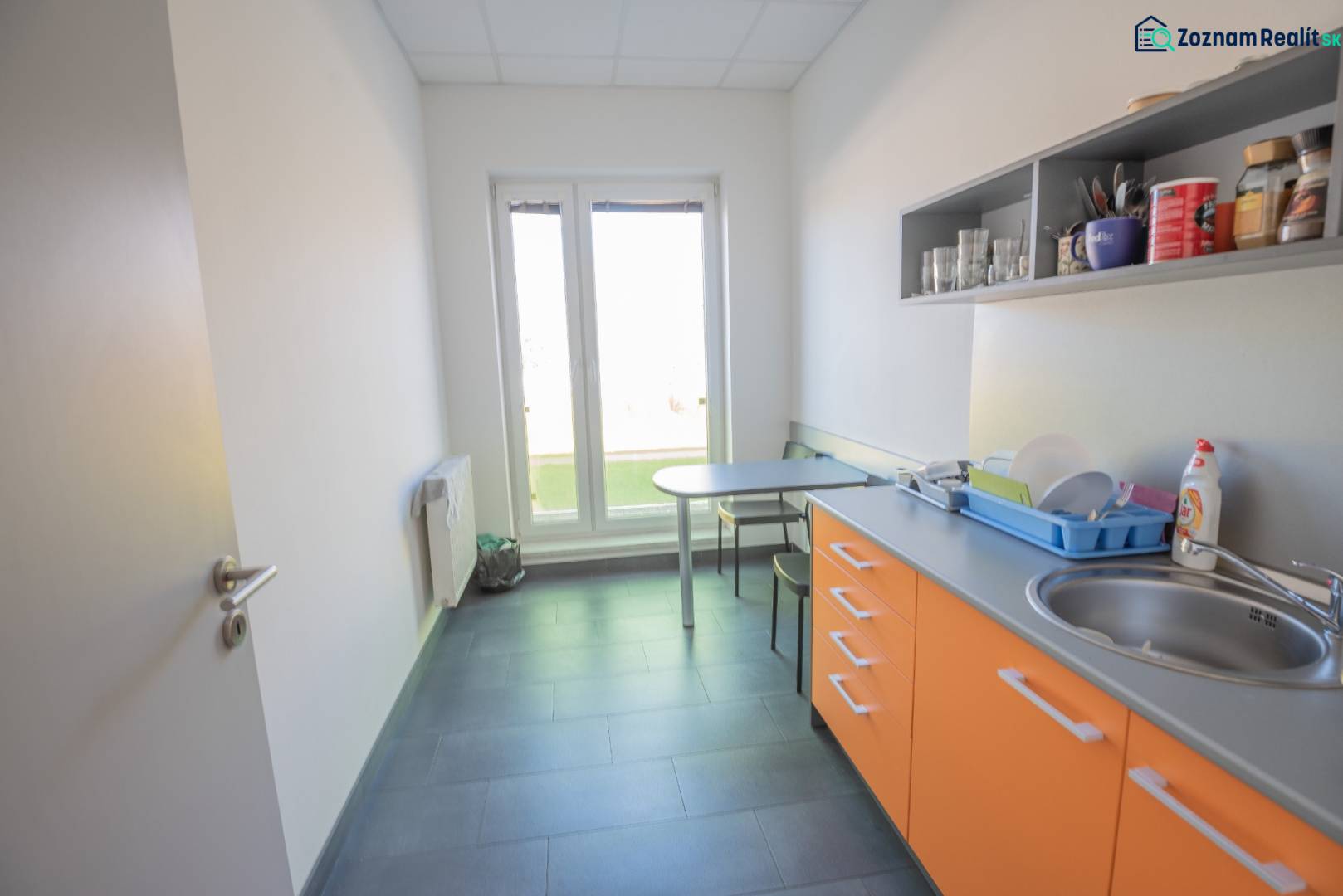 A kitchenette in the office with orange cabinets, a sink, and a seating table.