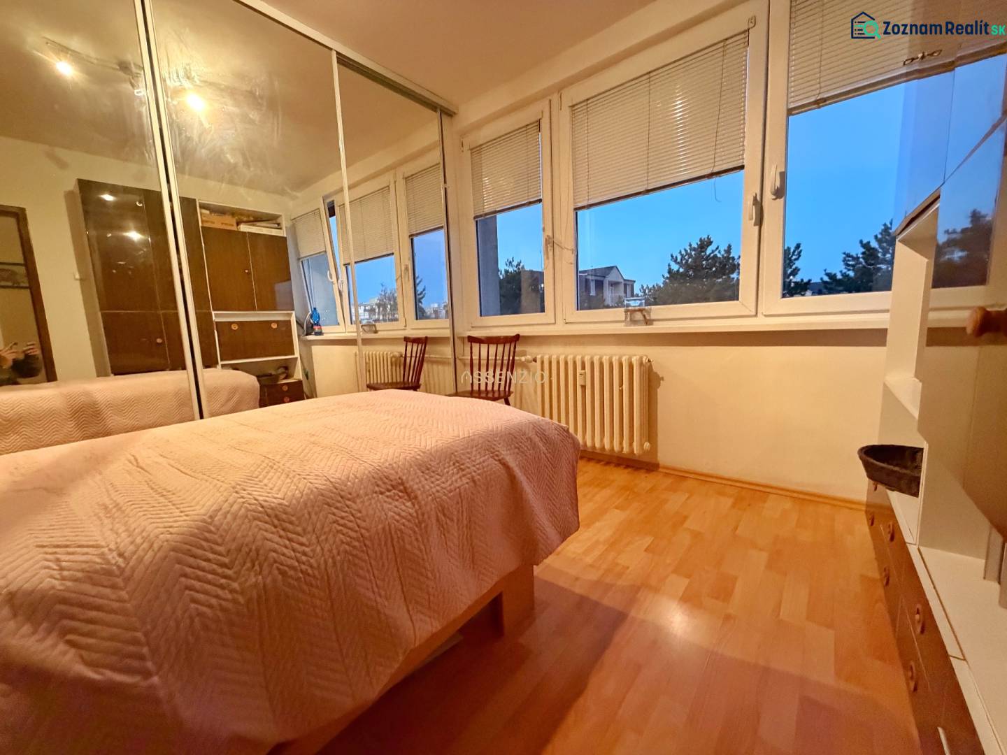 A bedroom in a 3-room apartment with a bed, wardrobe, and wooden decor flooring.