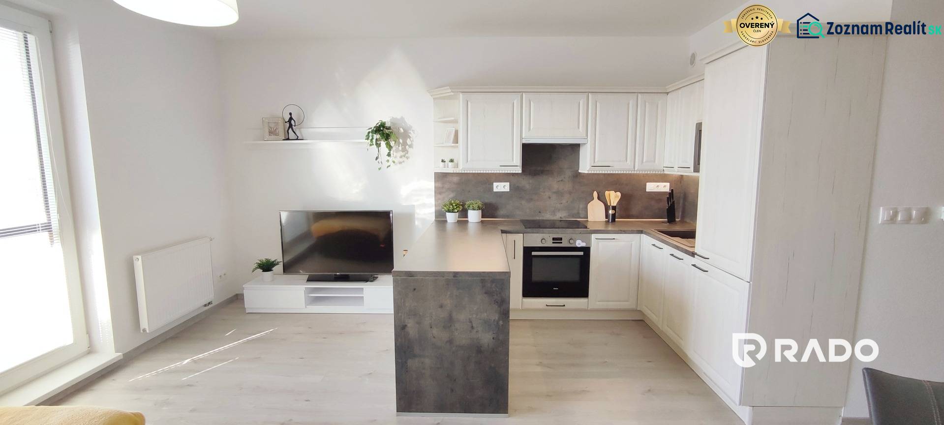 Living room with a kitchenette, light wooden-patterned floor in a 2-room apartment.