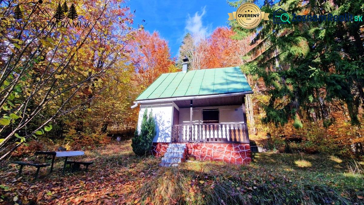 The cottage at Tály in Bystrá surrounded by colorful autumn nature with a bench in the foreground.