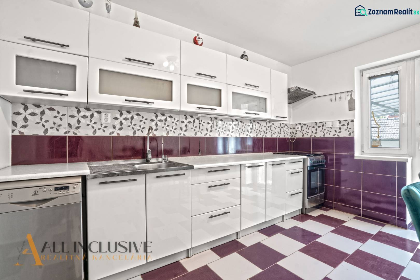 A kitchen in a family house with white cabinets, purple tiles, and built-in appliances.