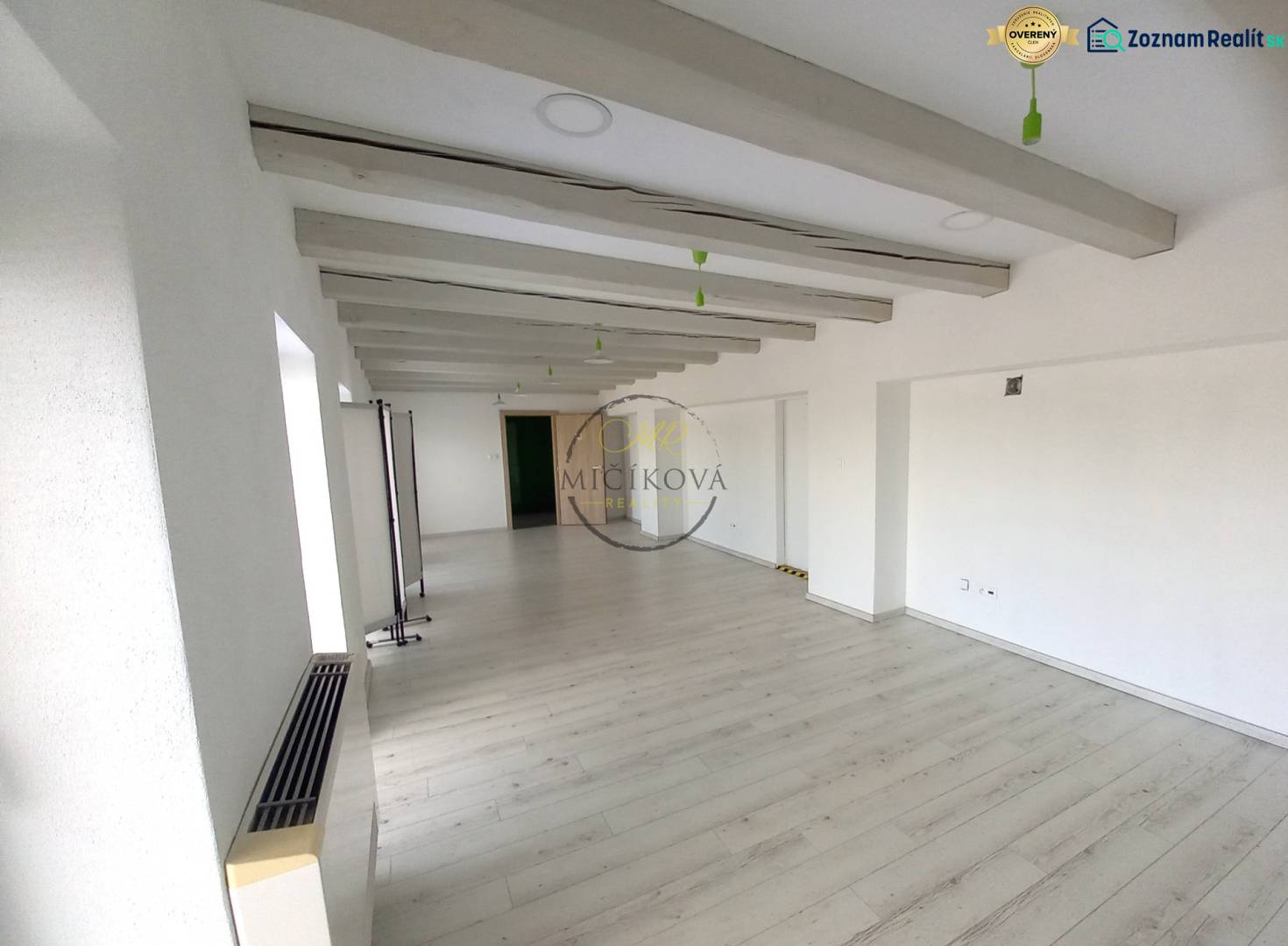 Empty office with white walls and wood-patterned flooring.