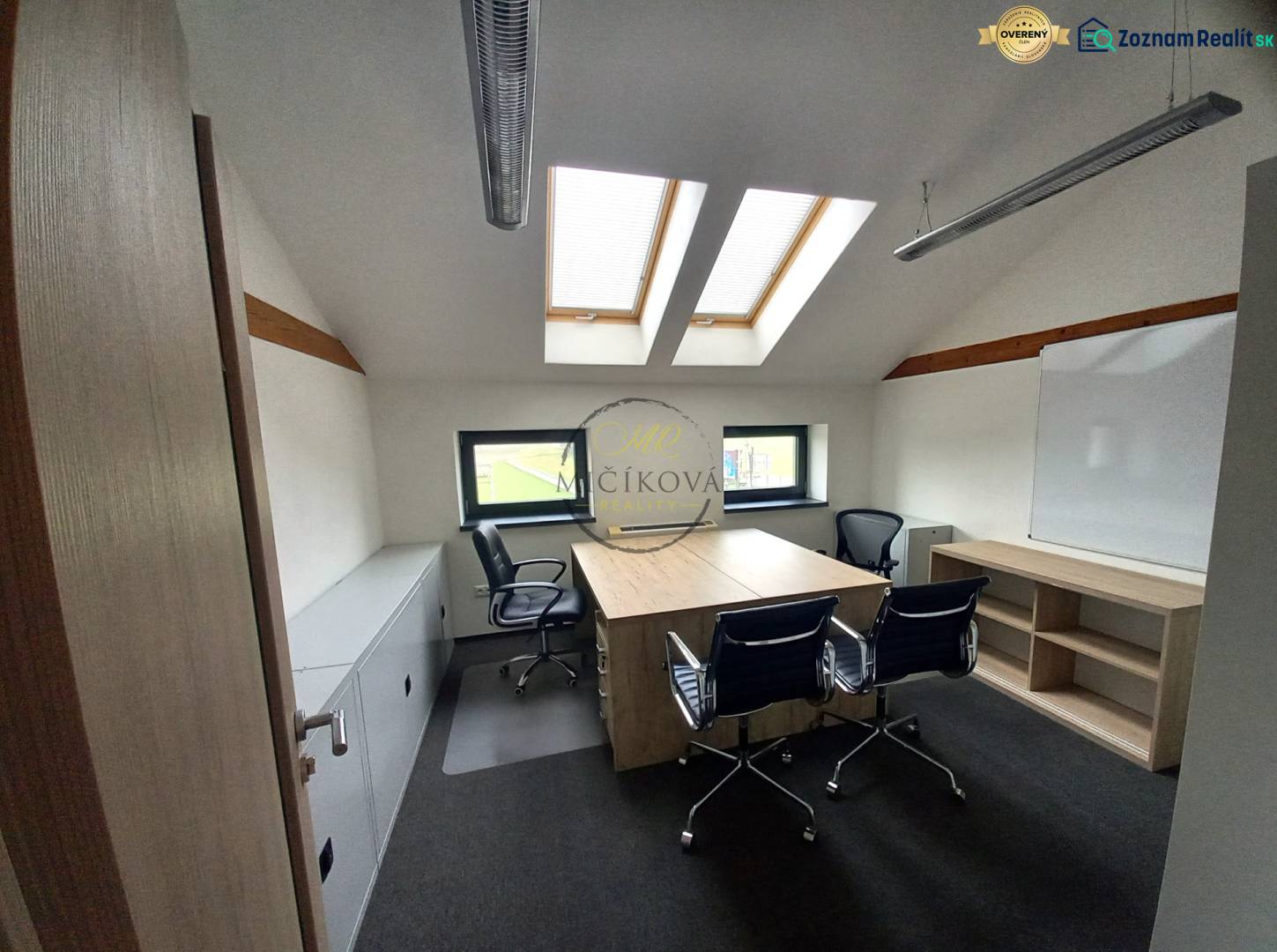 An office with a wooden floor design, skylights, and tables with chairs.