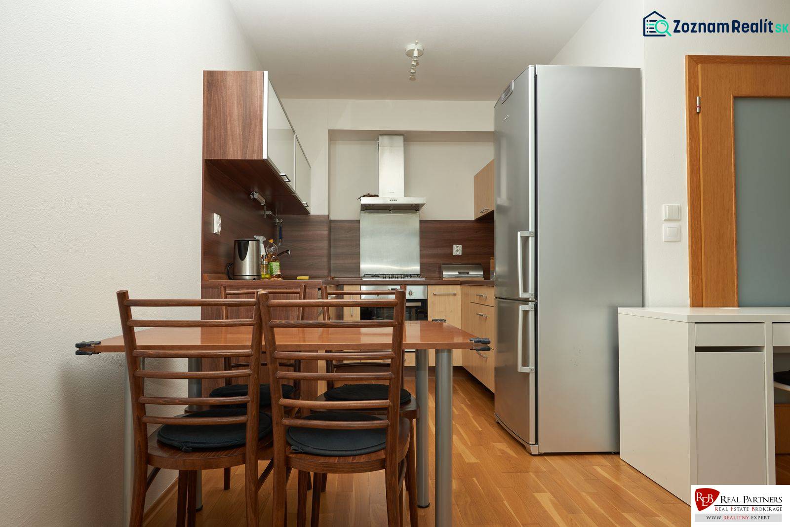 A kitchen in a 2-room apartment with a wooden decor floor and wooden furniture.
