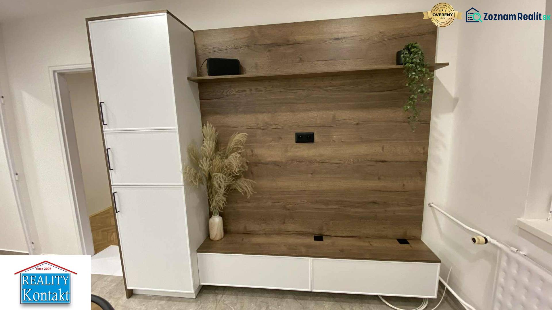 In the 1-room apartment, there is a wardrobe wall with a wooden decor and flowers in a vase.