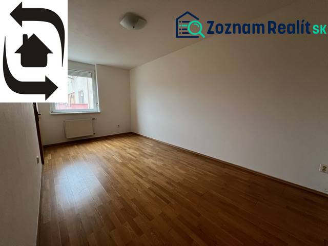 An empty room in a 3-room apartment with wooden flooring and a window.