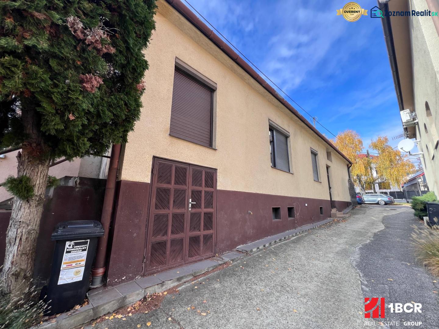 A family house in Bratislava-Rača with a garage and a tree by the road.