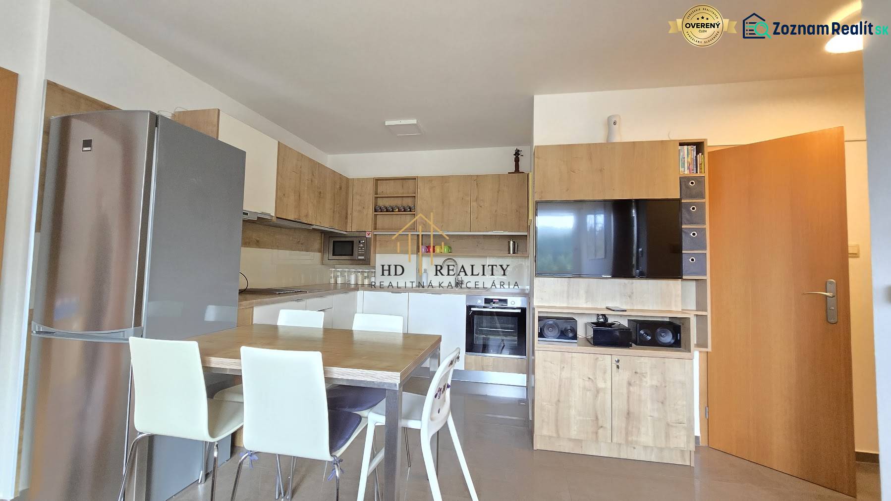 The kitchen of a three-room apartment with a wooden decor floor and a dining table.