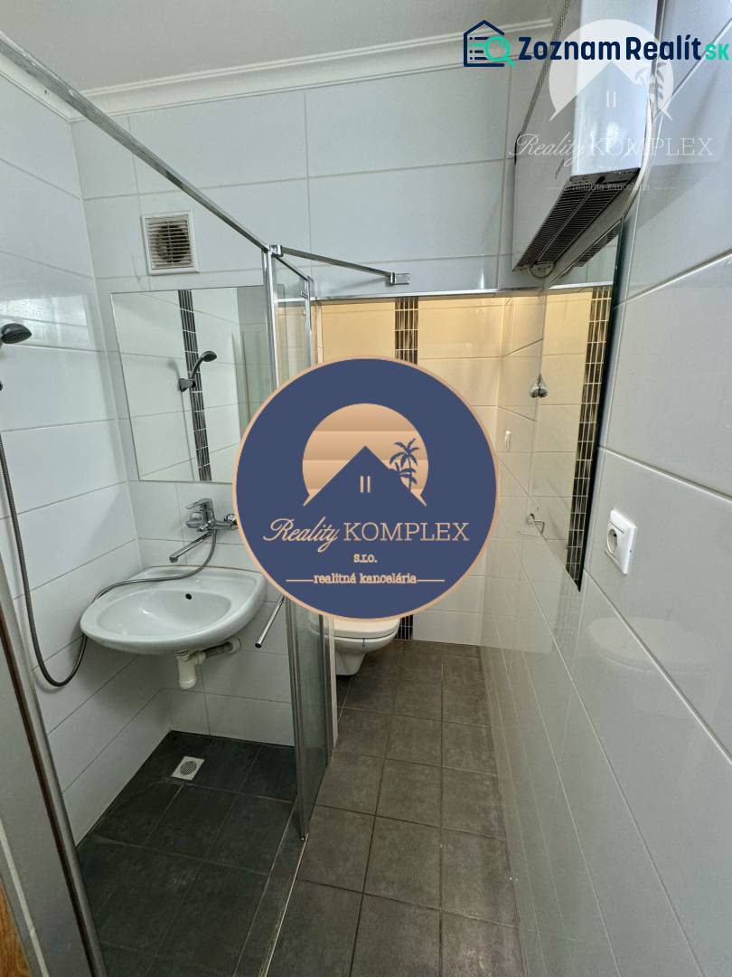 Bathroom with a shower and dark flooring in a studio apartment, white tiles.