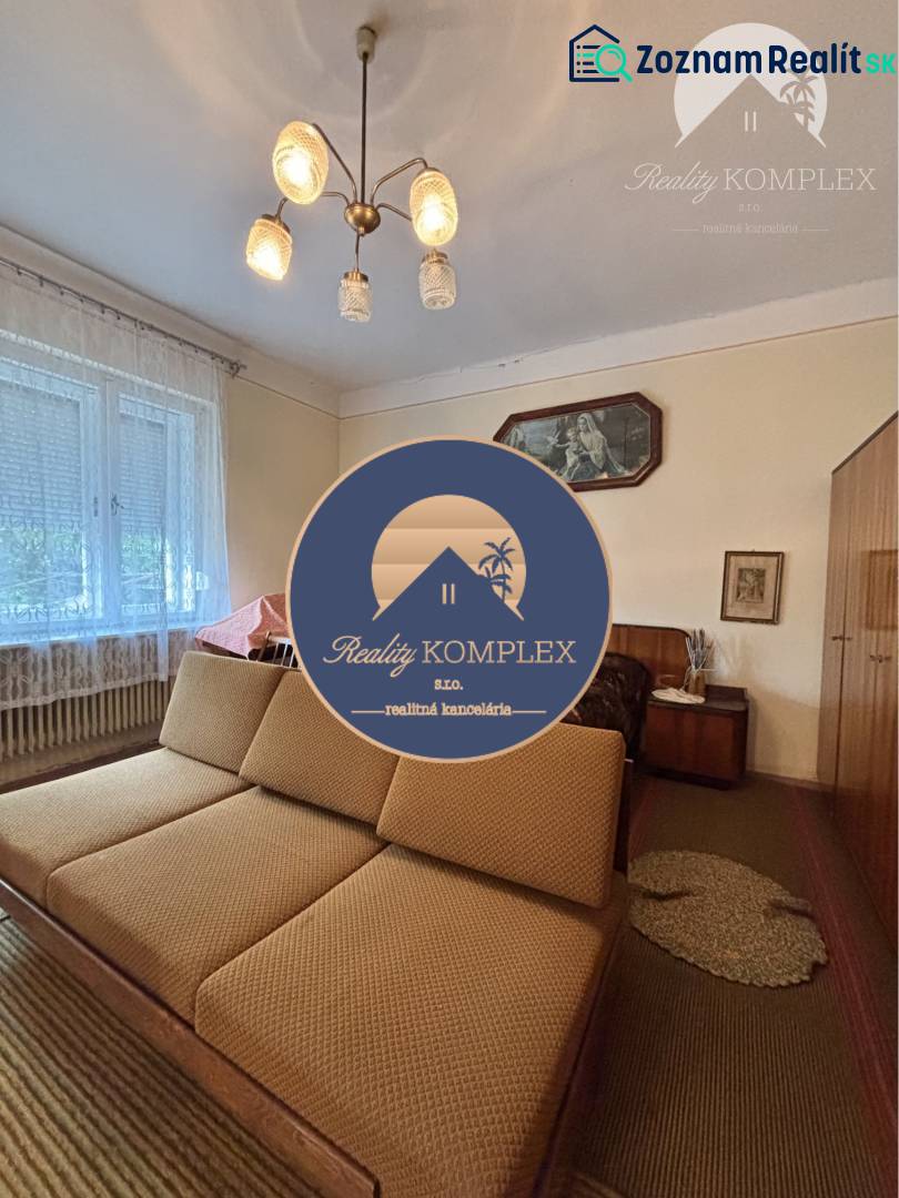 Living room in a family house with a sofa, chandelier, and light curtain on the window.