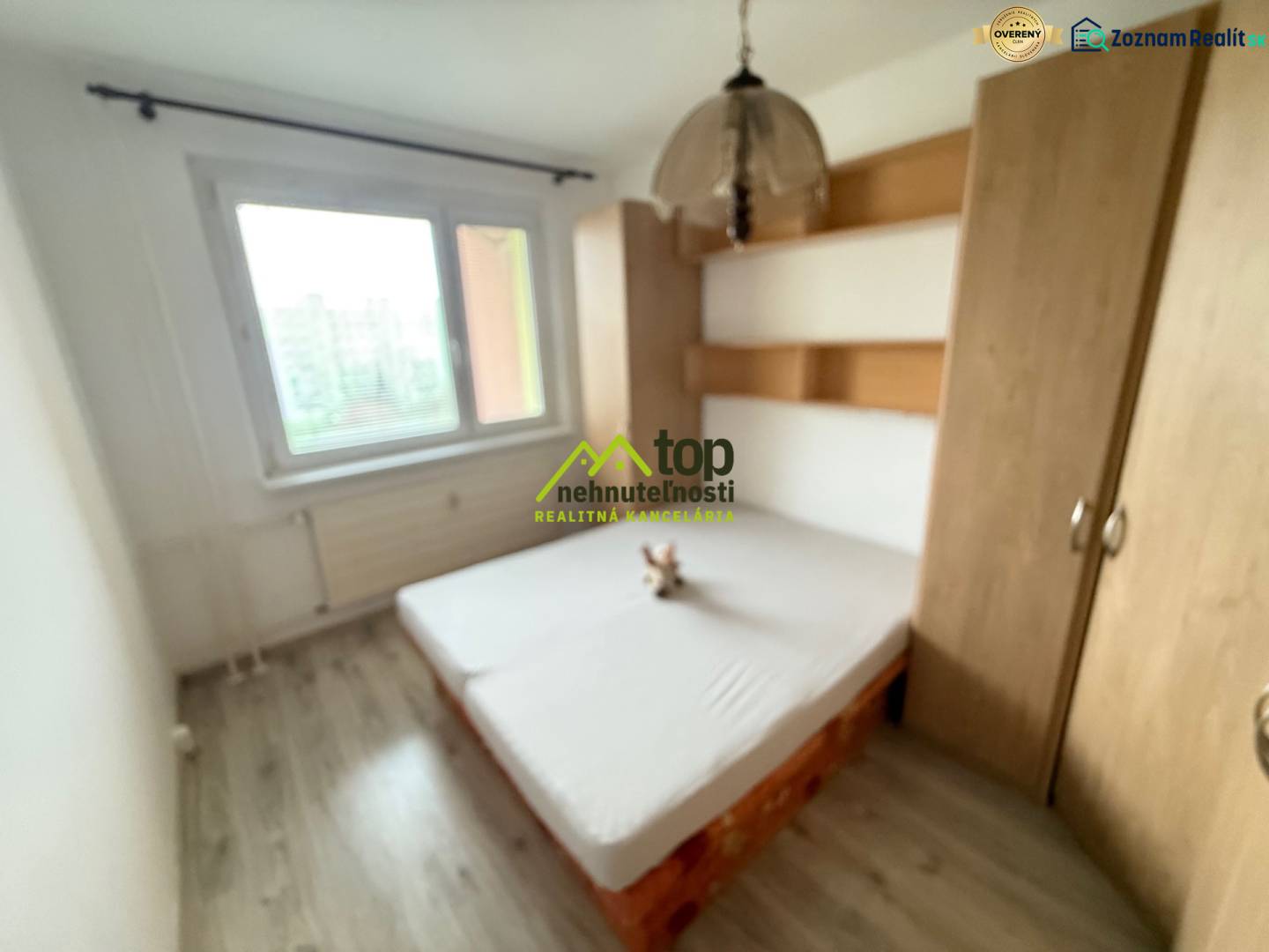 Bedroom with a bed and a wardrobe in a 2-room apartment with a wooden decor floor.