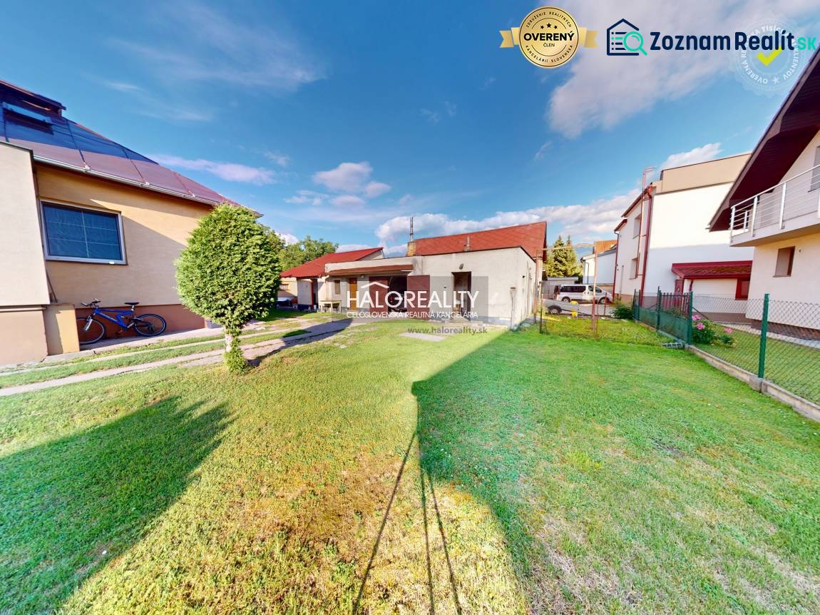 A garden at a family house in Krasňany with a lawn and a tree next to the building.