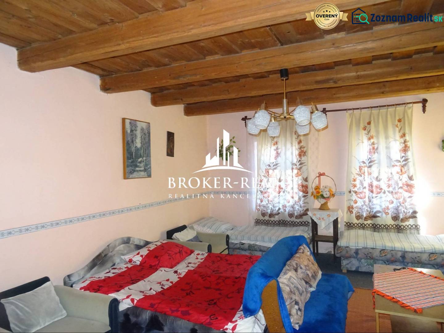 A room in a family house with a wooden ceiling, sofas, and colorful curtains.