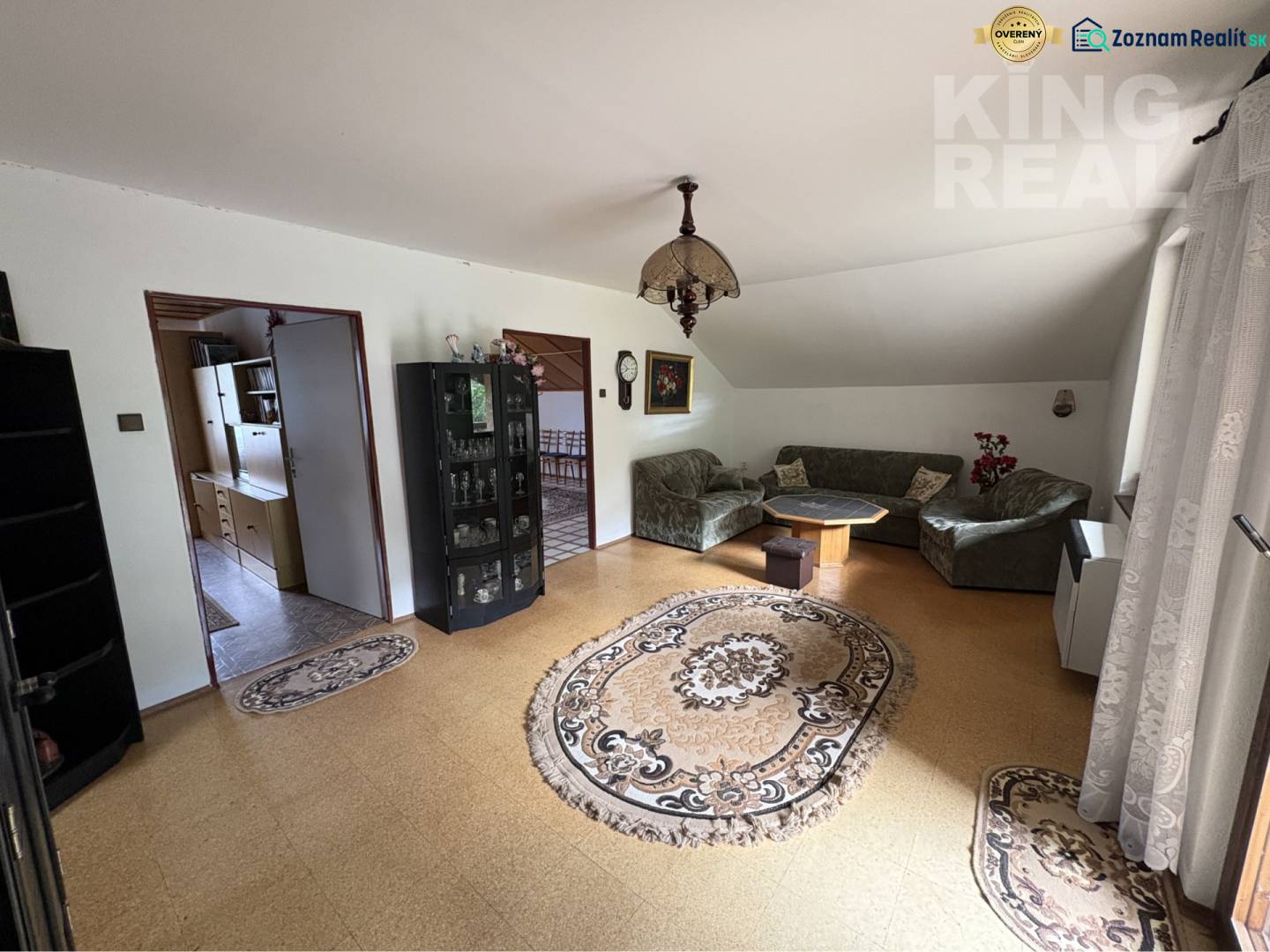 Living room in a family house with carpets, a sofa set, and a display cabinet.