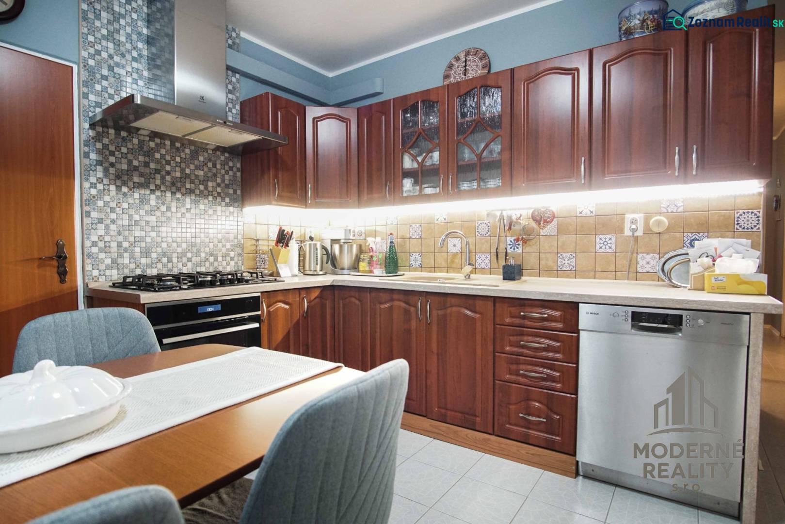 A kitchen in a 3-room apartment with wooden cabinets and a mosaic on the wall.