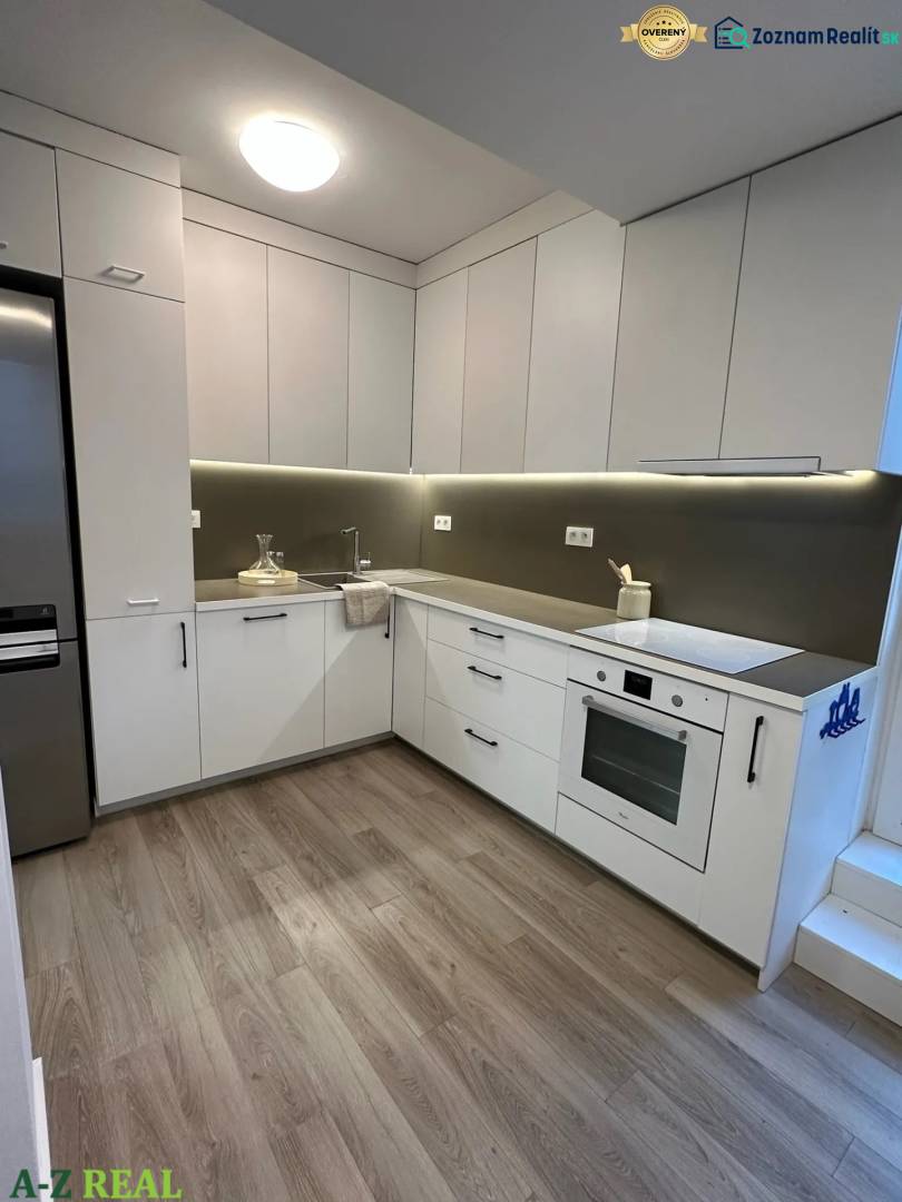 A kitchen in a 3-room apartment with built-in appliances and a floor with a wooden decor.
